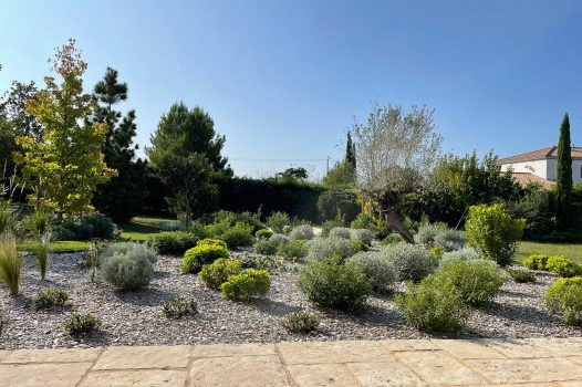 Réfection complète d’un jardin avec création d’un ensemble de massifs paysagers structurés et harmonieux. Les massifs sont composés de végétaux adaptés au climat local, mêlant persistants, vivaces, graminées et couvre-sols, pour un rendu à la fois esthétique, durable et facile d’entretien. Le travail de composition met en valeur les volumes, les textures et les couleurs selon les saisons. L’aménagement intègre également un paillage minéral ou organique selon les zones, assurant la gestion de l’humidité du sol et la limitation des adventices. Réalisation par un paysagiste professionnel pour sublimer l’espace extérieur avec une fontaine à poisson Valence Drôme Ardèche Rhône Alpes Paysagiste Pisciniste Dupré la Tour