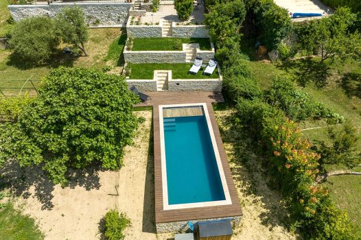 Réfection complète d’un jardin paysager comprenant la réalisation d’une piscine surélevée en structure modulaire Aquafeat, offrant robustesse et durabilité. Autour du bassin, une terrasse contemporaine est installée sur une structure métallique Terrassteel, supportant un platelage résistant et esthétique. L’aménagement est complété par la construction de plusieurs murs en pierre d’Eyzahut, maçonnés et jointés à la chaux avec un sable jaune, pour un rendu authentique rappelant l’appareillage en pierre sèche traditionnel. Ce projet combine savoir-faire paysagiste, techniques de construction modernes et intégration harmonieuse dans l’environnement naturel. Dupré la Tour / Drôme Ardèche / Paysagiste / Valence / Pisciniste