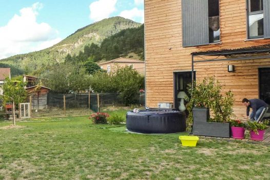 Création d’un espace bien-être extérieur avec l’installation d’un spa encastré à hauteur du sol, harmonieusement intégré dans un jardin paysager. Le spa est bordé par une terrasse en lames de bambou posée sur une structure métallique Terrassteel, assurant durabilité, résistance à l’humidité et finition soignée. Un mur en pierre naturelle vient structurer l’espace et renforcer l’ambiance authentique et chaleureuse. Des massifs paysagers complètent l’ensemble, avec notamment un olivier majestueux en élément central, apportant une touche méditerranéenne à la composition. Aménagement alliant confort, esthétisme et techniques modernes de construction extérieure. Ce projet illustre le savoir-faire d’un paysagiste et pisciniste en région Rhône-Alpes, intervenant à Valence, dans la Drôme et en Ardèche, pour des réalisations harmonieuses et techniques mêlant confort, tradition et modernité.