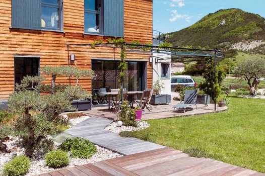 Création d’un espace bien-être extérieur avec l’installation d’un spa encastré à hauteur du sol, harmonieusement intégré dans un jardin paysager. Le spa est bordé par une terrasse en lames de bambou posée sur une structure métallique Terrassteel, assurant durabilité, résistance à l’humidité et finition soignée. Un mur en pierre naturelle vient structurer l’espace et renforcer l’ambiance authentique et chaleureuse. Des massifs paysagers complètent l’ensemble, avec notamment un olivier majestueux en élément central, apportant une touche méditerranéenne à la composition. Aménagement alliant confort, esthétisme et techniques modernes de construction extérieure. Ce projet illustre le savoir-faire d’un paysagiste et pisciniste en région Rhône-Alpes, intervenant à Valence, dans la Drôme et en Ardèche, pour des réalisations harmonieuses et techniques mêlant confort, tradition et modernité.