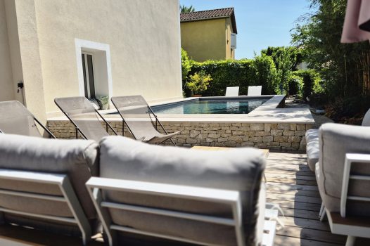 Piscine surélevée construite avec des panneaux modulaires Aquafeat, offrant une structure solide et durable pour un bassin hors-sol. L’ensemble est entouré d’un mur en pierre d’Eyzahut maçonné avec une finition en appareillage pierre sèche, assurant une parfaite intégration paysagère et une esthétique naturelle. La couverture du bassin est assurée par une bâche automatique immergée Aquagard, garantissant sécurité, protection et confort d’utilisation. À proximité immédiate, une terrasse contemporaine repose sur un lambourdage en structure métallique Terrassteel, avec un platelage en lames de bambou, matériau écologique et résistant. Aménagement extérieur complet alliant technicité, durabilité et design. Dupré la Tour piscine et paysage / Livron sur Drôme / Valence / Drôme Ardèche / paysagiste pisciniste