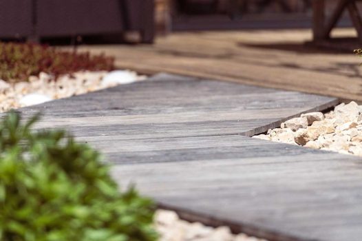 Création d’un espace bien-être extérieur avec l’installation d’un spa encastré à hauteur du sol, harmonieusement intégré dans un jardin paysager. Le spa est bordé par une terrasse en lames de bambou posée sur une structure métallique Terrassteel, assurant durabilité, résistance à l’humidité et finition soignée. Un mur en pierre naturelle vient structurer l’espace et renforcer l’ambiance authentique et chaleureuse. Des massifs paysagers complètent l’ensemble, avec notamment un olivier majestueux en élément central, apportant une touche méditerranéenne à la composition. Aménagement alliant confort, esthétisme et techniques modernes de construction extérieure. Ce projet illustre le savoir-faire d’un paysagiste et pisciniste en région Rhône-Alpes, intervenant à Valence, dans la Drôme et en Ardèche, pour des réalisations harmonieuses et techniques mêlant confort, tradition et modernité.